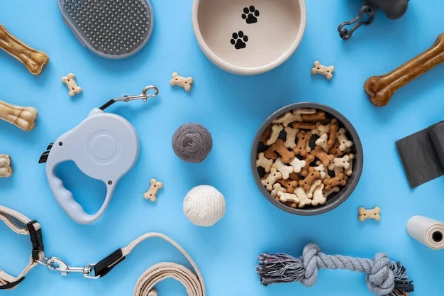 A bowl of dog food, treats, bone, leash, and pet waste bags on display indoors, with a blue background. This image serves as a pet products category banner for a pets paradise collection for cats and dogs.