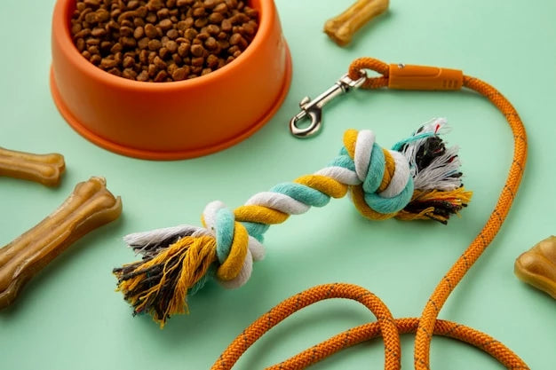 A dog toy, dry cat food in a bowl, a key chain, and a rope close-up. Indoor, handmade items visible. This serves as the Pets Paradise Banner for the pet products collection "Collars & Leash".