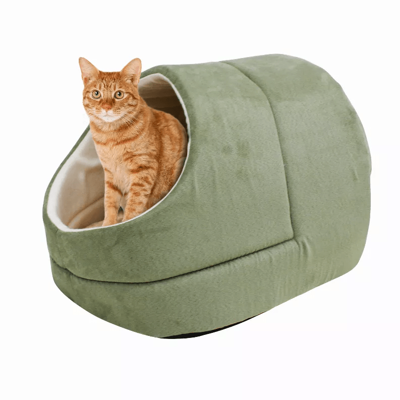 An orange tabby cat sitting inside a green Pets Paradise Elite Warming Burrow Suede Cat Cave Bed with a semi-enclosed design.